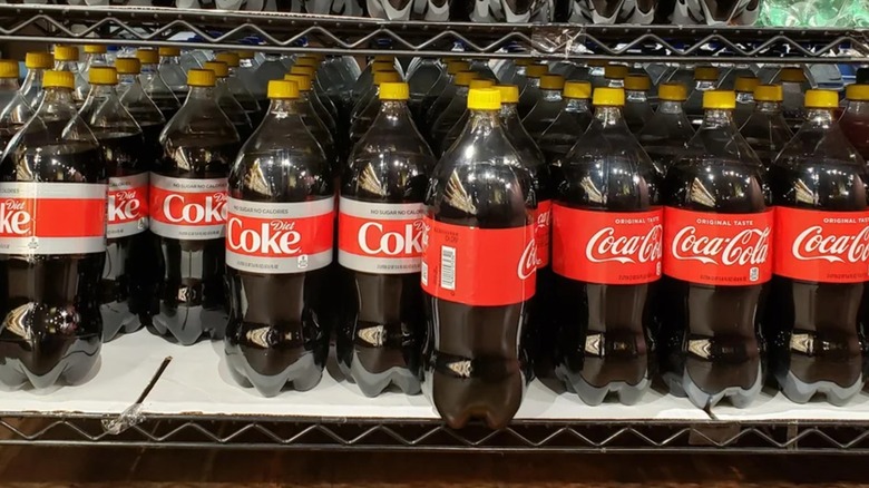 2-liters of diet and regular Coca-Cola with yellow caps on them at a store.