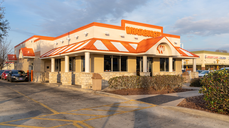 The exterior of a whataburger location with cars in the drive thru