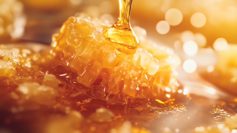 Closeup of honeycomb being drizzled with honey