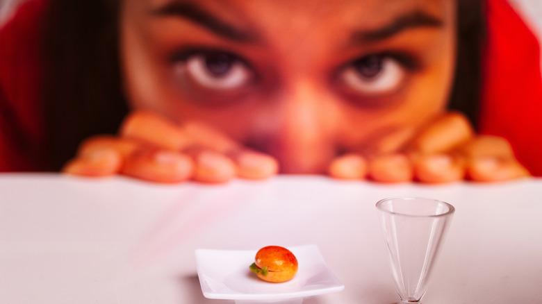 A person staring at a small portion of food on a tiny plate