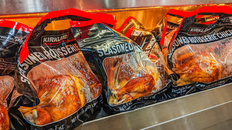 Many Costco rotisserie chickens sit on a shelf in their plastic bags