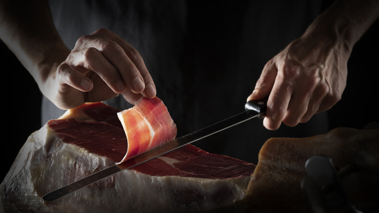 slicing off a piece of Serrano ham leg