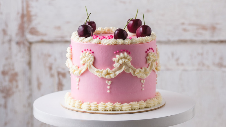 Lambeth-style cake in pink with cream and hot pink piping, decorated with cherries on top.