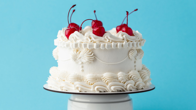 Lambeth-style cake in white with white piping and red cherries on top.