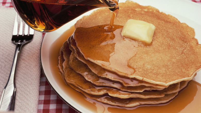 Stack of delicious pancakes on plate isolated on white