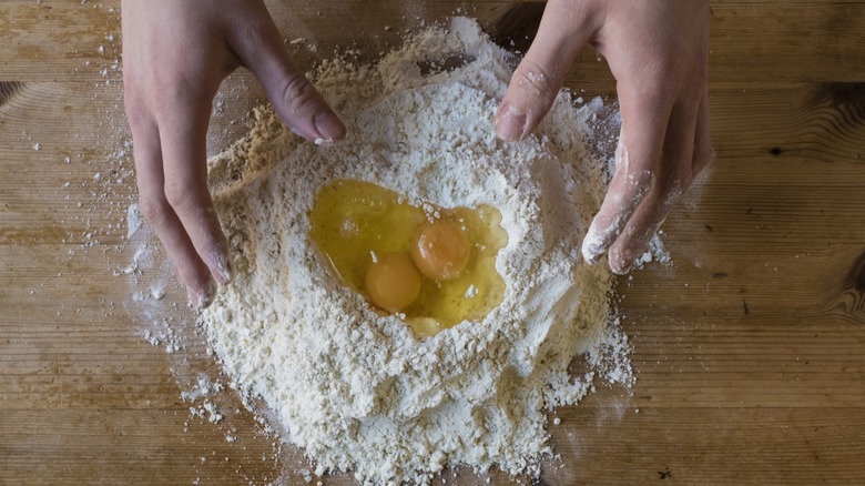 A person about to knead eggs into flour to make pasta