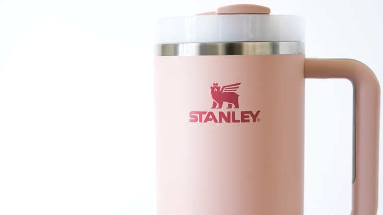 A close-up of a pink Stanley cup, showing the mythical bear logo.