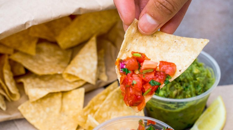 hand holding chip with salsa