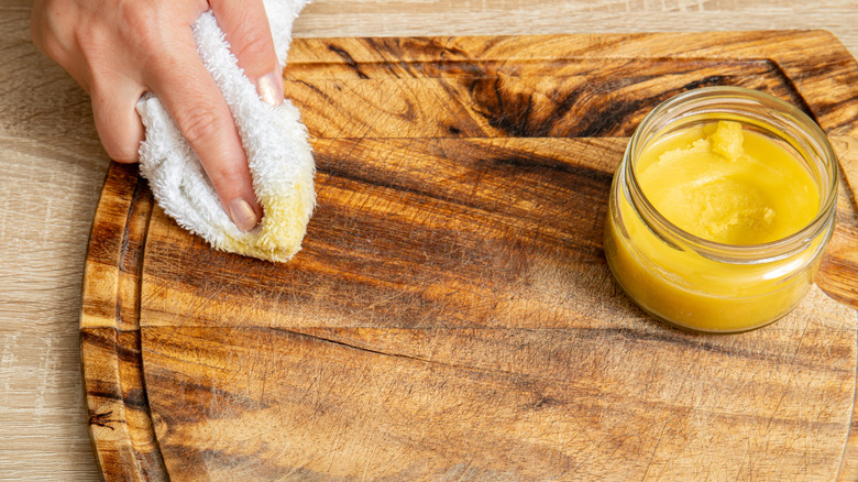 hand wiping beeswax on cutting board