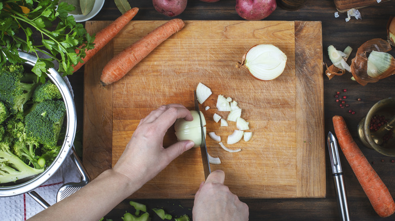 hands chopping vegetables on wooden cutting board