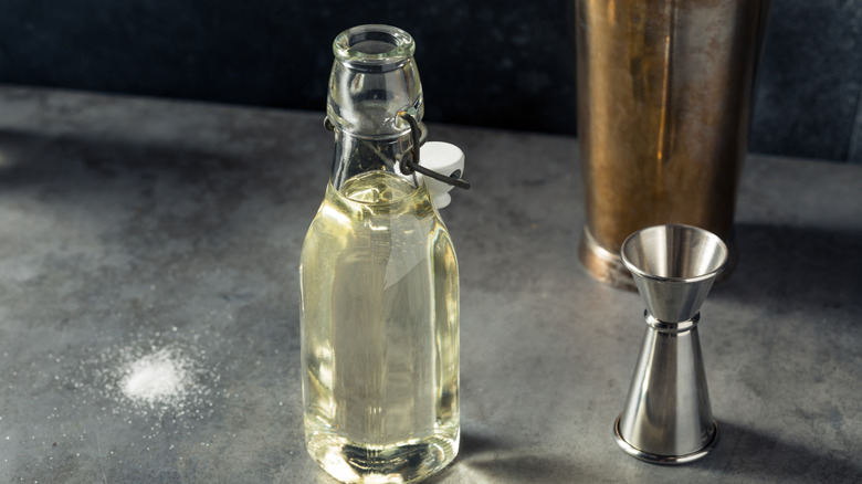 swingtop bottle of simple syrup next to jigger and cocktail shaker