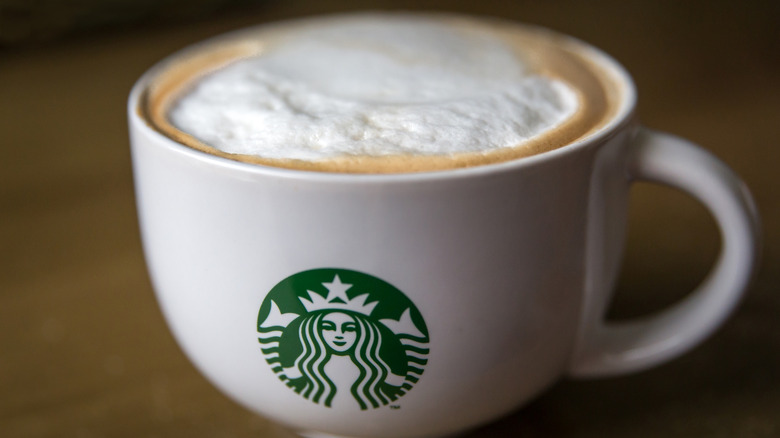 A Starbucks cup with the store's logo placed on a dark wood table