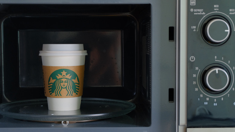 A Starbucks coffee drink sits in an open microwave.