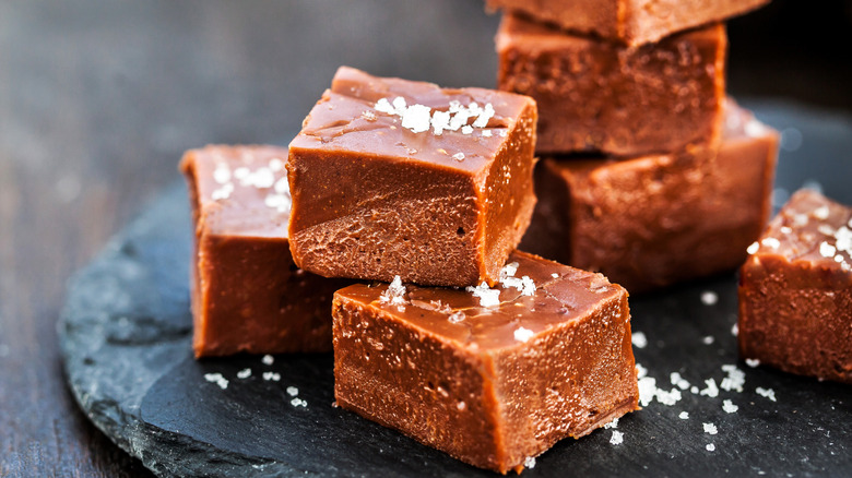 Homemade chocolate fudge with sea salt on a black slab.