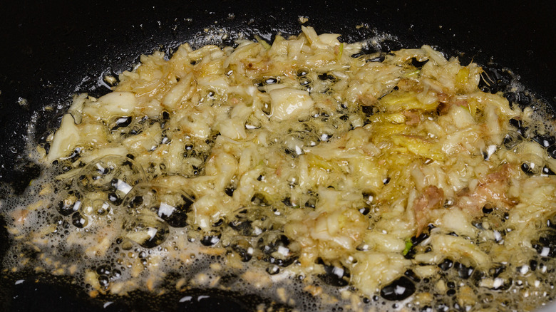 Pieces of garlic frying in a pan.