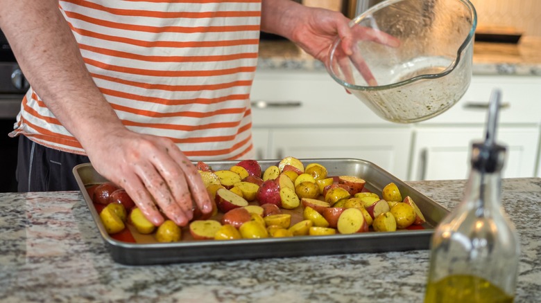 Person's hands putting potatoes on a sheet pan