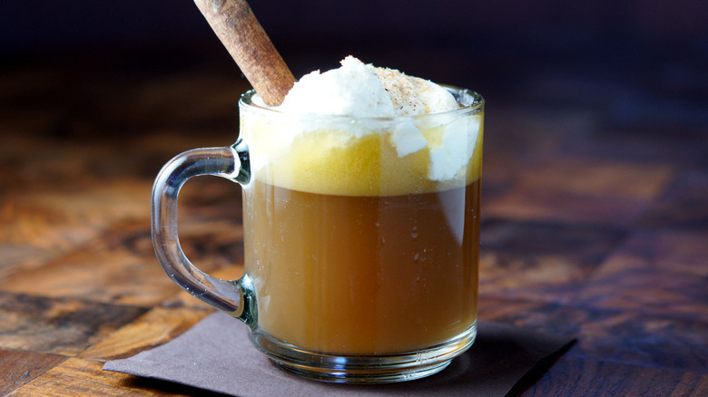 Hot buttered rum served in a glass cup with whipped cream.