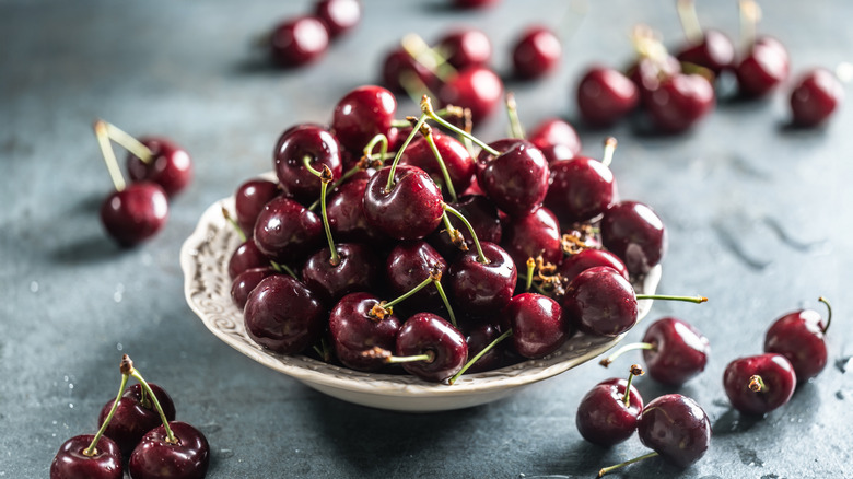 A bowl of cherries sitting on a table.