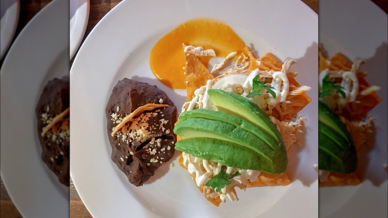 Chilaquiles topped with avocado and side of black beans