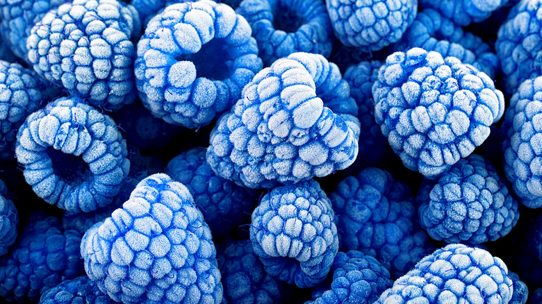 A close-up photo of a pile of frozen blue raspberries