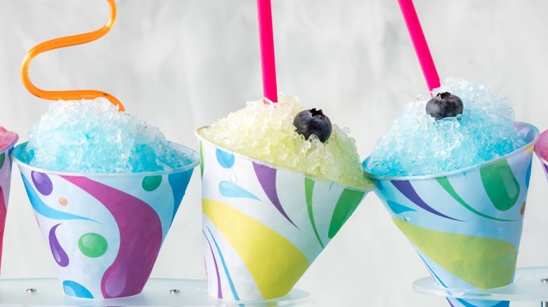 Three snow cones in colorful paper, two in blue raspberry flavor