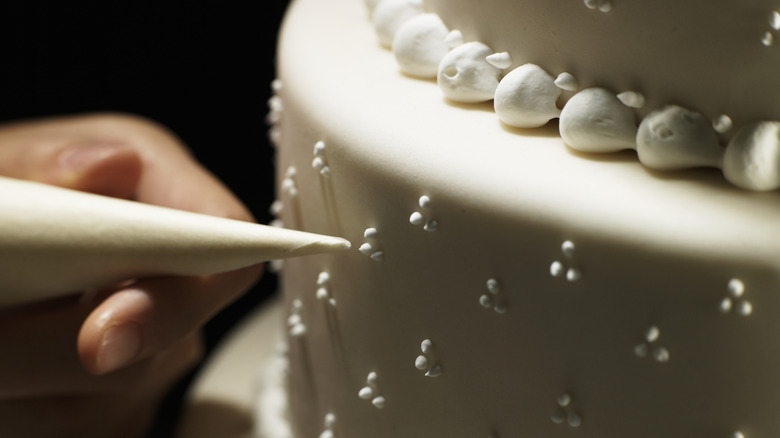 Hand piping royal icing onto white cake