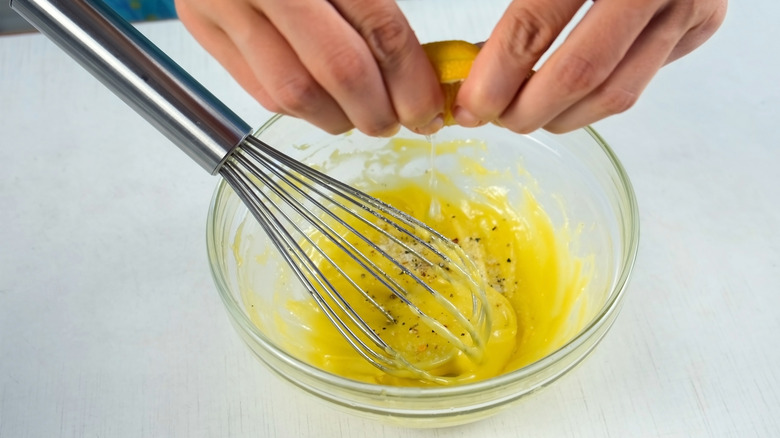 A person cracking an egg into a bowl.