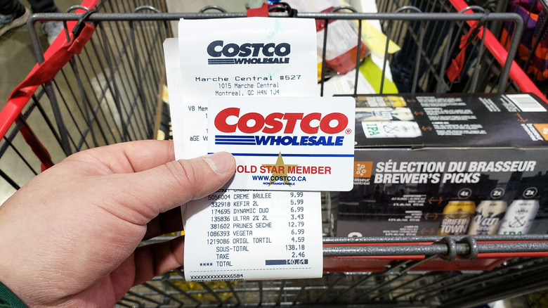 a Costco receipt and membership card in front of a costco shopping cart