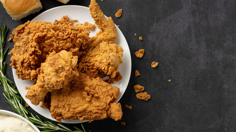 Bird's eye view of a plate of fried chicken with bits of it falling off the plate