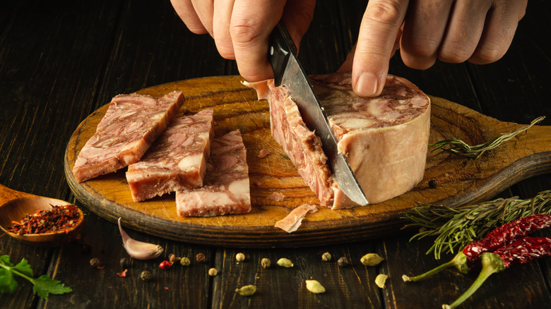 Hands slicing a round of head cheese