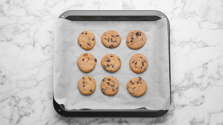 Chocolate chip cookies sitting on parchment paper in a pan.