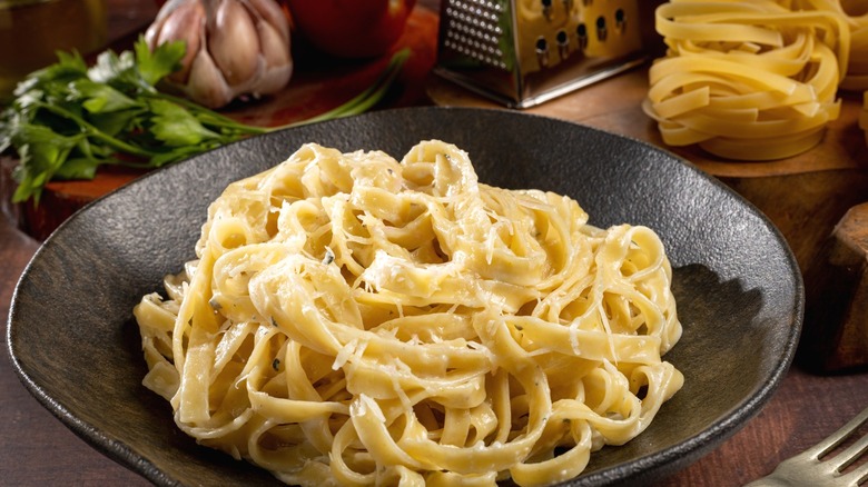 A bowl of fettuccine Alfredo pasta sprinkled with parmesan