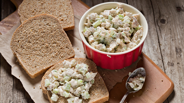 A bowl of chicken salad with slices of bread