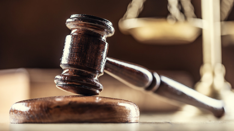 a wooden gavel with a set of scales in the background