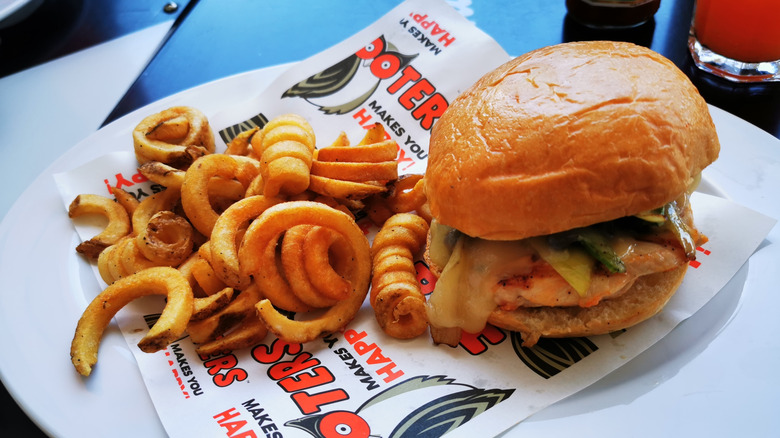 A Hooters chicken sandwich and curly fries on a plate