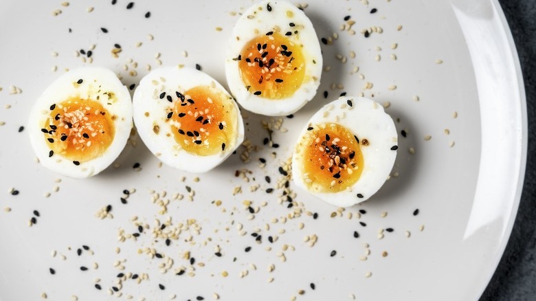 Boiled eggs with sesame seeds on plate.