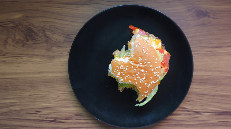 A half eaten burger sits on a black plate