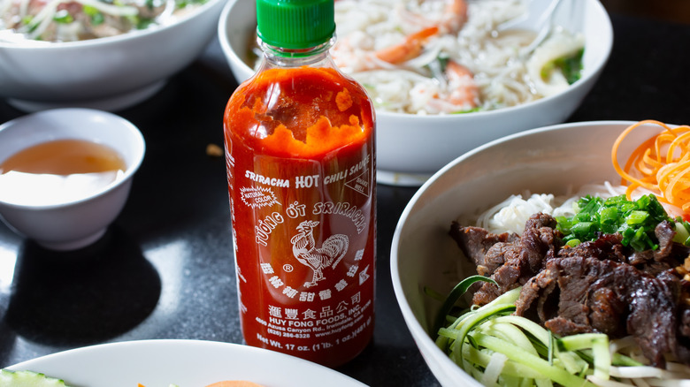 Hot sauce bottle sits between dishes on a table