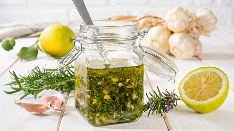 Homemade salad dressing in a jar with rosemary, garlic, and lemon