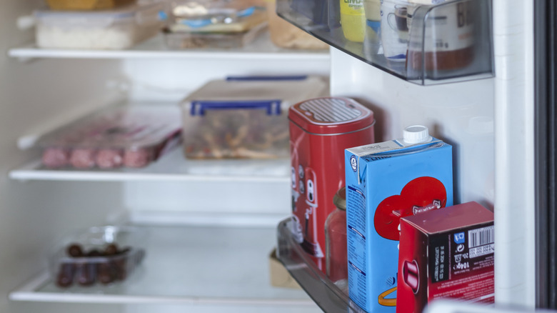 An open fridge, with the fridge door in focus, full of condiments and food packets.