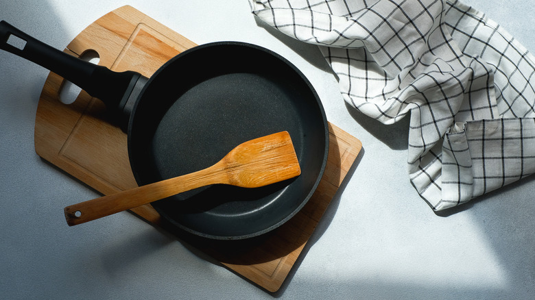 Cast iron skillet with a wooden spatula inside on a cutting board