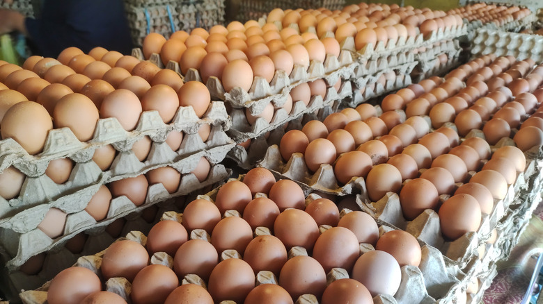 Large cartons of eggs are stacked on top of each other in a market