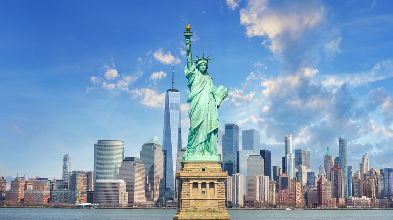 The Statue of Liberty, with the Manhattan skyline in the background.