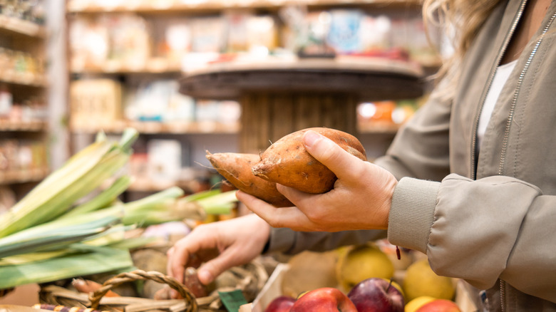 woman picking sweet potatoes in the produce section