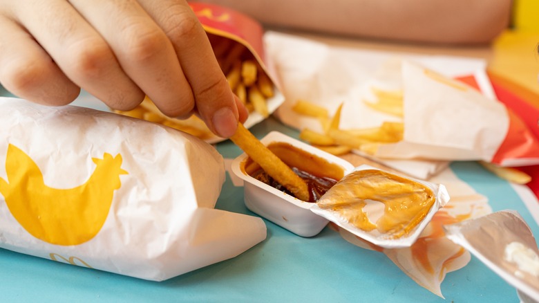 Fingers dipping french fry into dipping sauce