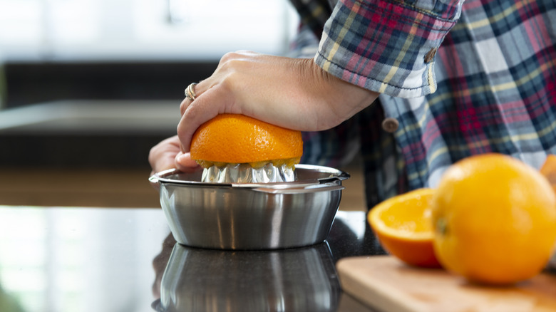 Person's hands juicing oranges with a citrus juicer