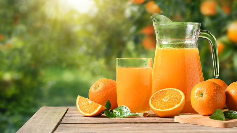 Freshly squeezed orange juice in a jug and glass with oranges