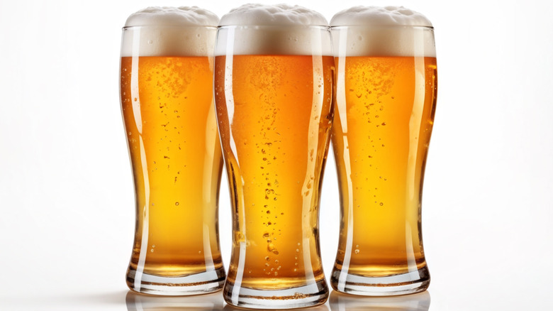 Three tall pint glasses of beer against a white background