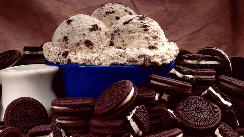 A pile of Oreo cookies with a heaped bowl of Oreo ice cream in the background