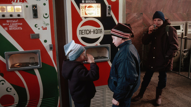 Children drink Pepsi in glass cups from a vending machine